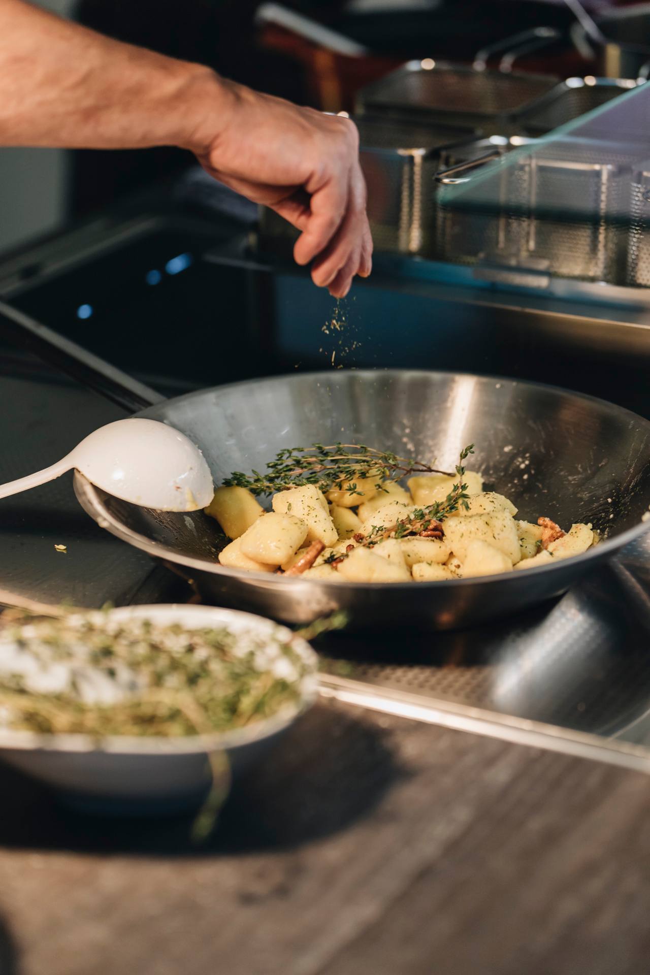 Ein Koch schwenkt Gemüse in einer großen Pfanne – Live-Cooking in der Kochwerkstatt